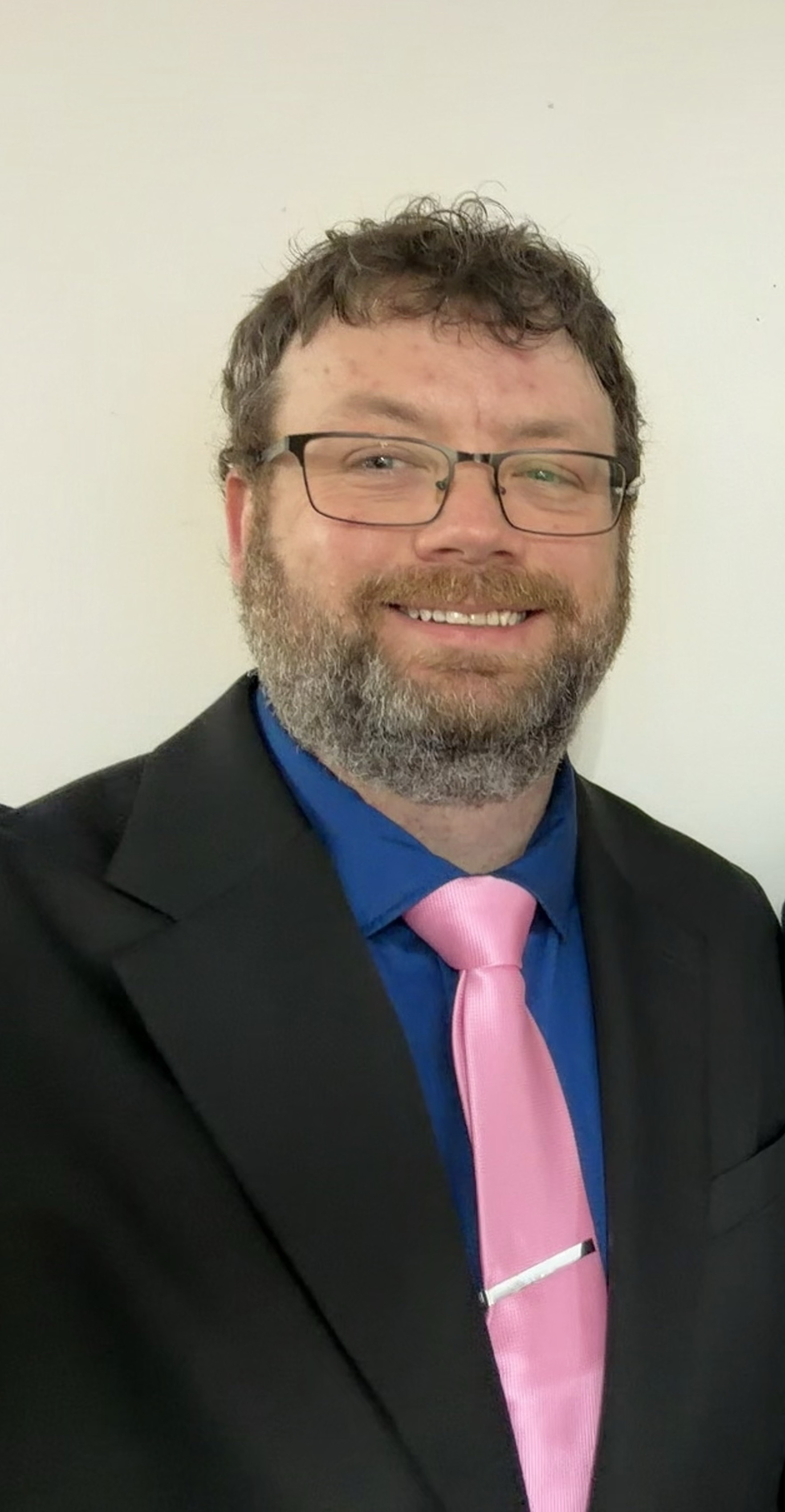 Trent King smiling, wearing a blue shirt and suit jacket
